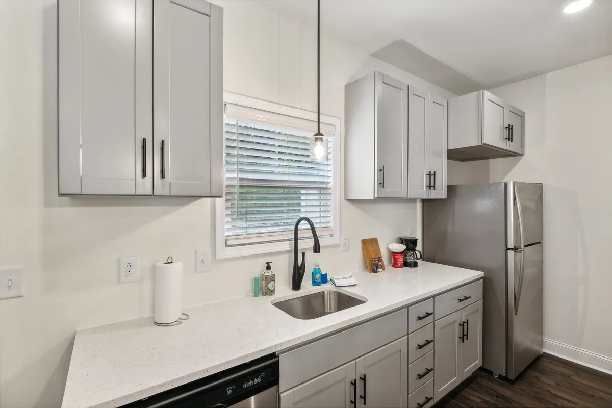 This image displays a welcoming kitchen scene with a kitchen sink, countertop, cabinetry, and a refrigerator. The arrangement invites shared meal preparation and family gatherings, underscoring the role of the kitchen as a hub for connection and hospitality.